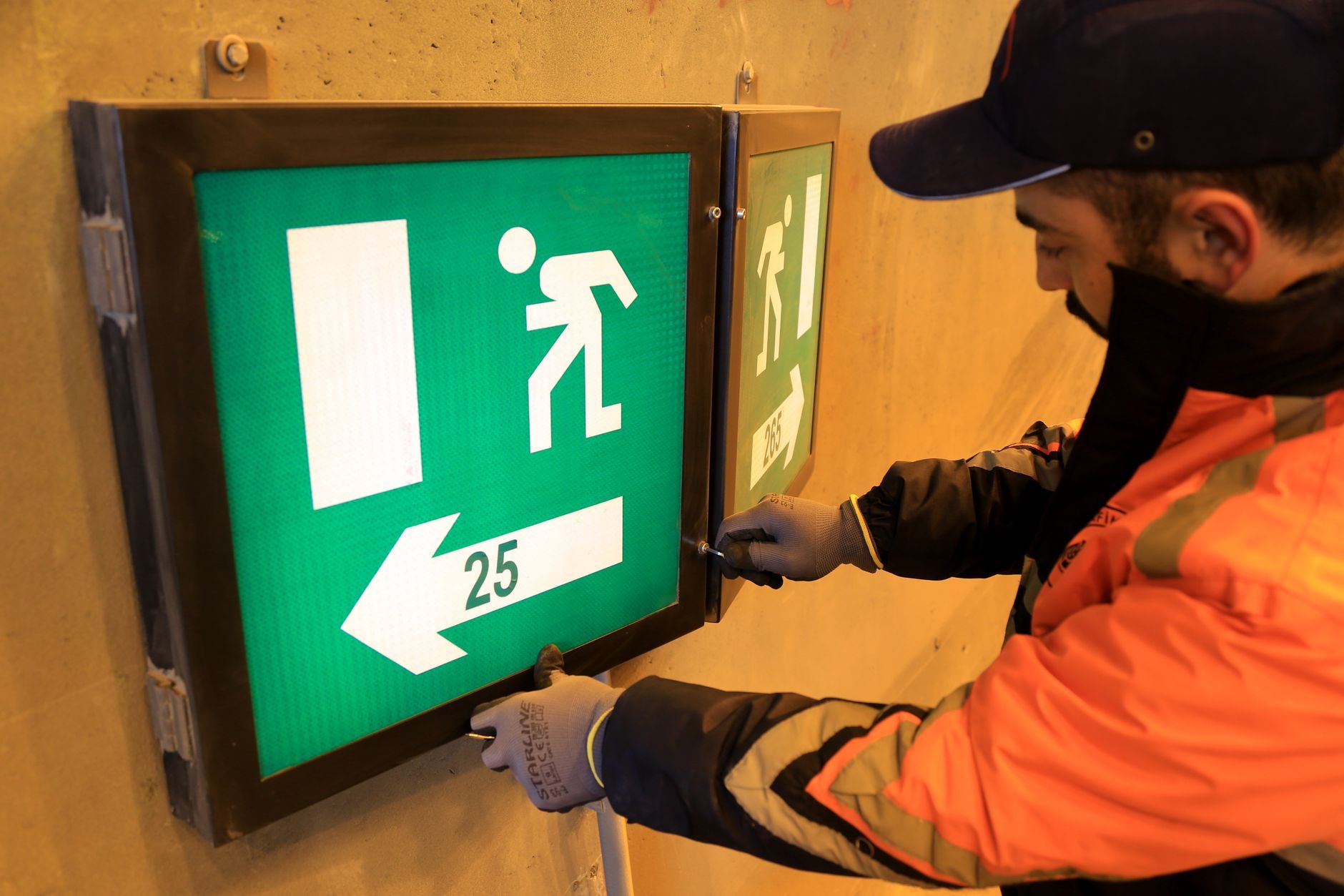 Emergency electrician repairing a sparking outlet with safety gloves and tools during a nighttime home service call